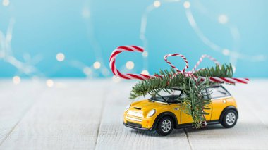 Köknar dallı oyuncak araba ve mavi arka planda lolipop.