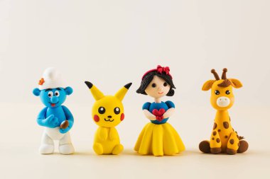 Açık bej arkaplanda polimer kilden yapılmış çizgi film karakterlerinin oyuncak figürleri