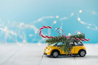 Köknar dallı oyuncak araba ve mavi arka planda lolipop.