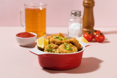 Tabakta çıtır nugget ve pembe arka planda sert gölgeli ketçap..