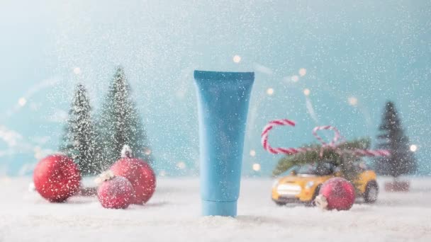 Stop-motion. Burla de un tubo azul con un producto cosmético con nieve que cae. — Vídeos de Stock