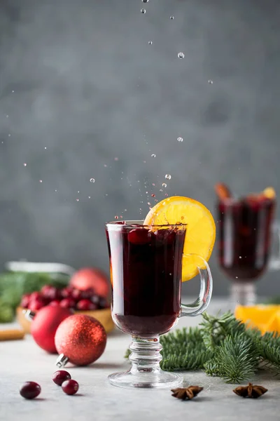 Splash de um bakal com vinho ruminado rodeado de temperos, flor de laranja e ramos de uma árvore de Natal. — Fotografia de Stock