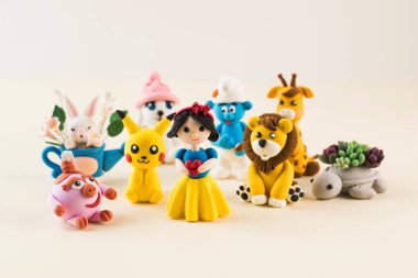 Açık bej arkaplanda polimer kilden yapılmış çizgi film karakterlerinin oyuncak figürleri