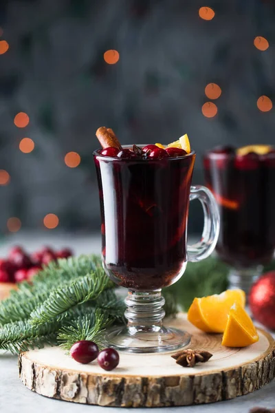 Copos com vinho caseiro mulled em um fundo de Natal com ramos de uma árvore de Natal, cranberries e bokeh. — Fotografia de Stock