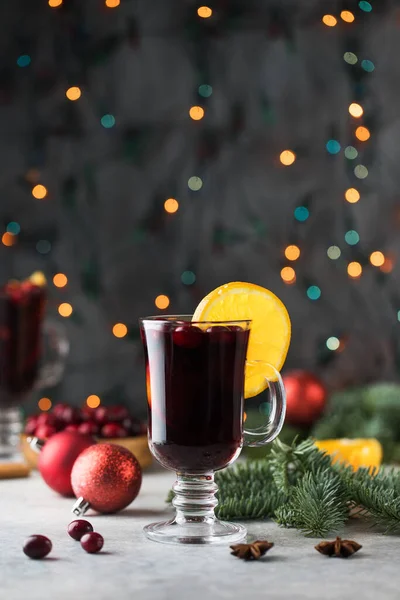 Copos de vinho ruminado com cranberries e um pau de canela em um fundo de Natal com bokeh. — Fotografia de Stock
