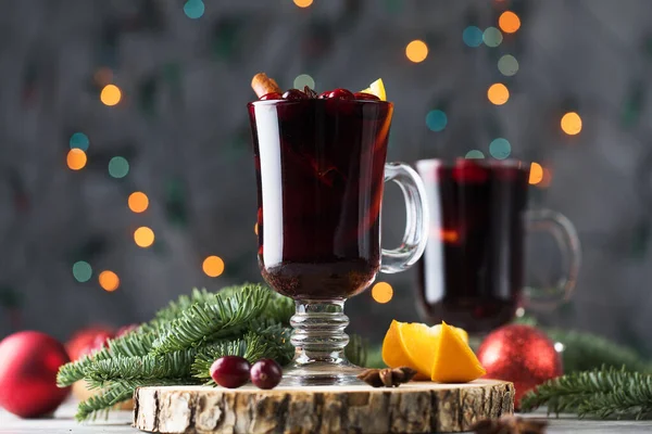 Glasses of mulled wine with cranberries and a cinnamon stick on a Christmas background with bokeh. — Fotografia de Stock