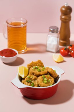 Tabakta çıtır nugget ve pembe arka planda sert gölgeli ketçap..