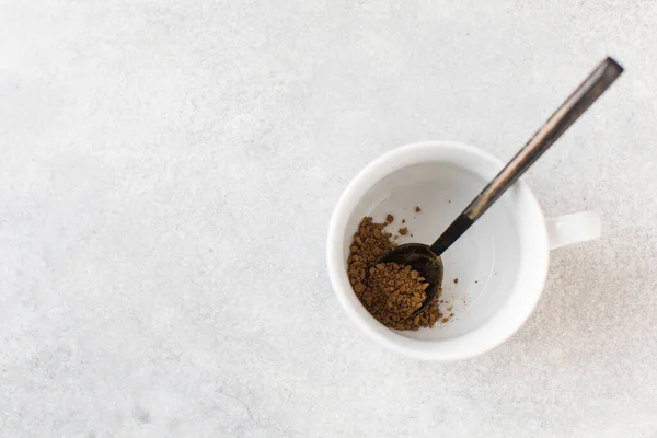 Instant coffee in a spoon in a white mug. View from above. Copy space. — Photo