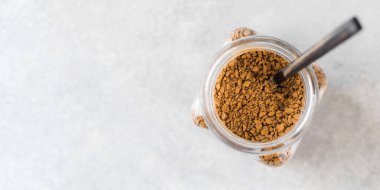 Glass jar of instant coffee with a spoon top view. Copy space.