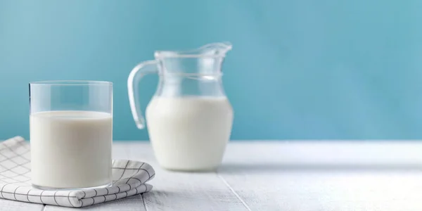 A jug and a glass of fresh milk on a blue background. — стоковое фото