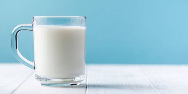 Banner of a mug of fresh milk on a blue background. Copy space.