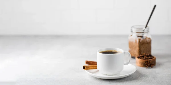 灰色のテーブルの上にソーサーにシナモンスティック付きの白いマグカップのブラックコーヒー。スペースのコピー. — ストック写真