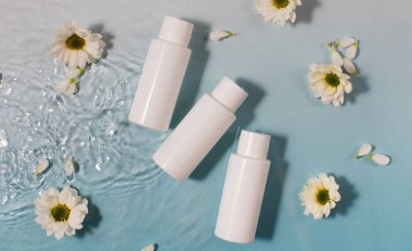 Kozmetik ürünleri ve taze papatya çiçekleri açık mavi yüzey ve temiz su