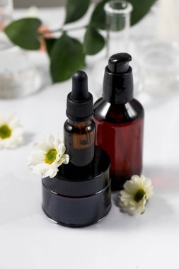  Organik kozmetik ürünleri suyun üzerinde, beyaz çiçeklerin ve bir bitkinin yanında duruyor..