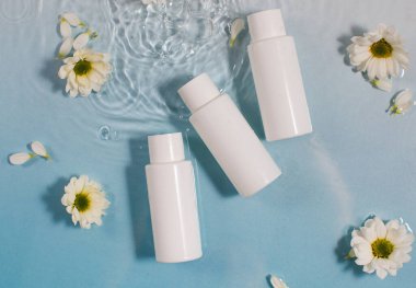 Kozmetik ürünleri ve taze papatya çiçekleri açık mavi yüzey ve temiz su