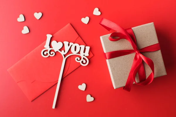 Coffret cadeau plat laïc, enveloppe et un signe avec les mots que je t'aime sur un fond rouge. Le concept de Saint-Valentin. — Photo