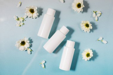 Kozmetik ürünleri ve taze papatya çiçekleri açık mavi yüzey ve temiz su