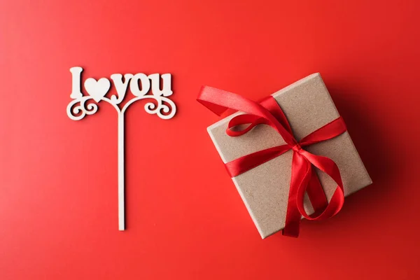 Flat lay caixa de presente e um sinal com as palavras que eu te amo em um fundo vermelho. O conceito de Dia dos Namorados. — Fotografia de Stock