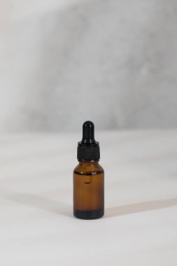 Açık gri arka planda yüz derisi için serumu olan kahverengi cam damlası. Bakım kozmetikleri.