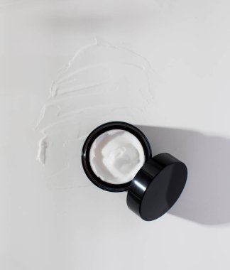 Beyaz krem lekesi üzerine açık bir tensel nemlendirici kavanozu. Doğal kozmetik konsepti.