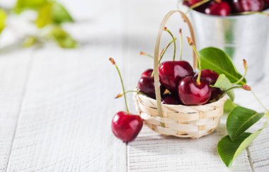 Tahta bir arka planda sepetin içinde olgun kirazlar. Boşluğu kopyala.