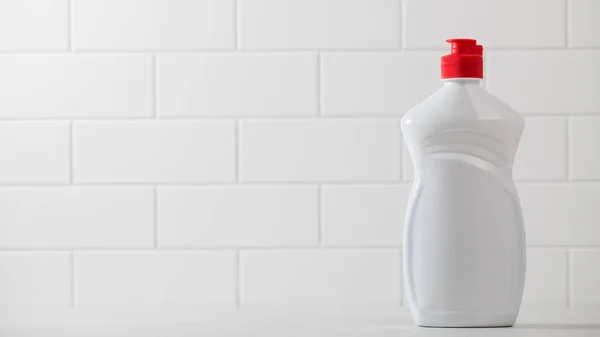 A mockup of a white plastic bottle with liquid dishwashing detergent with a white tiled background. Copy space. — Stock Photo, Image