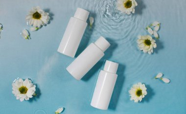 Kozmetik ürünleri ve taze papatya çiçekleri açık mavi yüzey ve temiz su