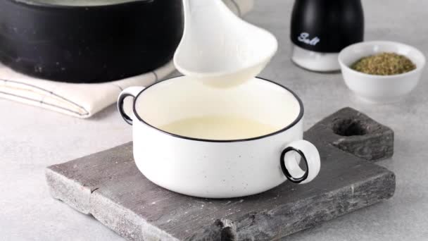 Налейте ковш здорового домашнего костяного бульона в белую миску. — стоковое видео