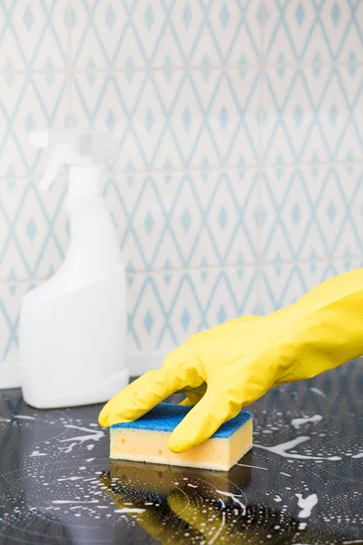 Un limpiador en un guante amarillo lava una cocina con una esponja y espuma. Limpiador de cocina blanco maqueta. — Foto de Stock