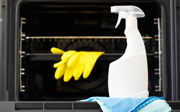 On the door of an open oven is a mock-up of a white spray bottle with oven detergent. General cleaning of the kitchen.