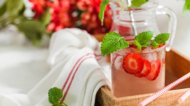 Sürahi ve bardakta ev yapımı taze çilekli limonata.