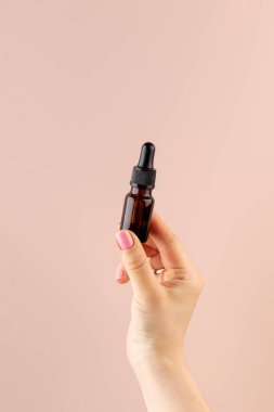 Bir kadının elinde deri yağı olan kahverengi bir damlanın maketi..