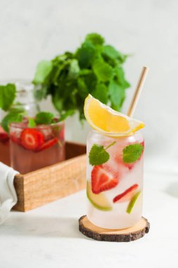Hafif arka planda çilek, limon ve nane aromalı ferahlatıcı bir yaz içeceği. Çilekli limonata.
