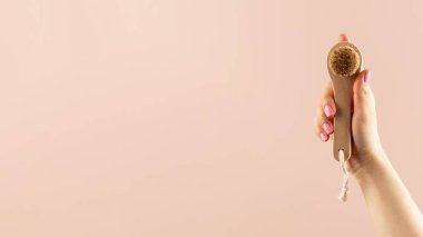 Bir kadının elindeki doğal kıllardan yapılmış kuru yüz fırçası derisini yüzmek. Soyunma, yüz derisi için detoks..