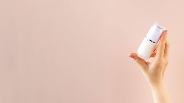 Pembe arka planda bir kadının elinde bir kavanoz nemlendiricinin maketi. Boşluğu kopyala. 