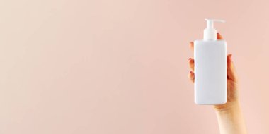 Açık pembe arka planda bir kadının elinde kozmetik ürünü olan beyaz bir şeker kutusunun maketi..