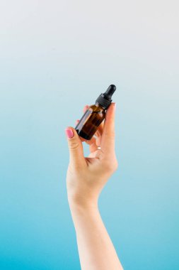 Bir kadının elinde deri yağı olan kahverengi bir damlanın maketi..