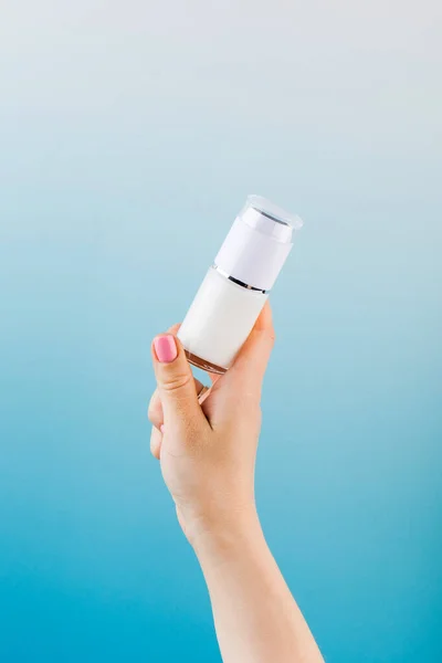 A mock-up of a jar of moisturizer in a womans hand on a blue background.