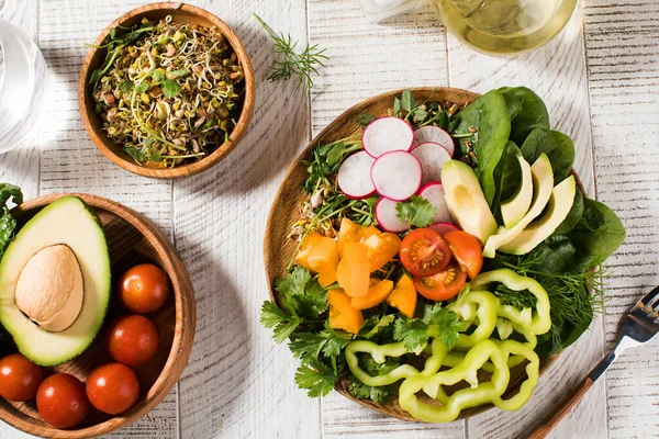 Növényi nyári saláta avokádóval, szezonális zöldségekkel, spenóttal és mikrozöldséggel, fa fehér alapon. — Stock Fotó