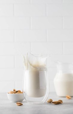 Hafif arka planda bademli sebze sütüyle bardağa su sıçrat. Sağlıklı yaşam tarzı kavramı.