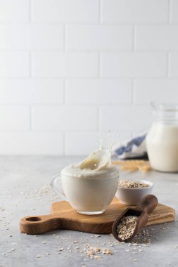 Bitkisel yulaf sütüyle bardaktan damlıyor. Vejetaryen sütü.