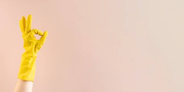 Sarı lastik eldiven, bej arka planda iyi niyet göstergesi. Profesyonel temizlik servisi. Kolay ev işleri ve rutin ev işleri