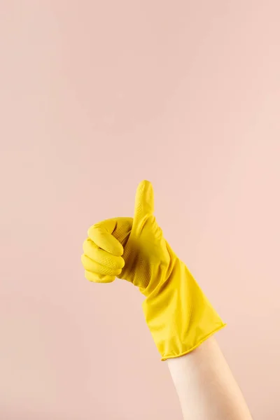A hand in a yellow rubber glove for washing and cleaning shows a thumbs up. Cleaning concept.