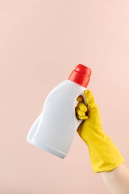 Pembe bir eldivenin üzerinde sarı lastik bir eldivenin içindeki bir şişe jelin maketi..