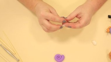 Masadaki turuncu polimer çamurdan yapılmış salyangoz kafaya gözlerini dikiyor.