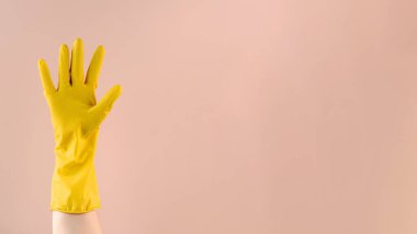 Sarı lastik eldiven, bej arka planda parmakları olan iyi bir jest olduğunu gösteriyor. Boşluğu kopyala