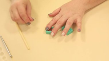 Kadın zanaatkar çam kozalağı yapıyor. Yeşil silikon kalıba kahverengi polimer kil koyuyor.