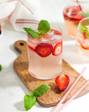 Ev yapımı taze çilekli limonata bardakta ve taze çilek ve nane yapraklı sürahi. Yaz içeceği. Boşluğu kopyala.