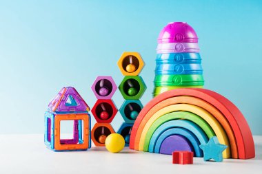 Çağdaş oyuncaklar mavi arka plandaki bebekler için oynanacak ve geliştirilecek. Tahta oyuncaklar, piramit ve inşaat seti yakın çekim. Anaokulu ekipmanları