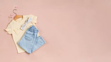 Kotlu, aksesuarlı ve pembe arka planda sarı tişörtlü çocuksu bir imaj. Düz yatıyordu.